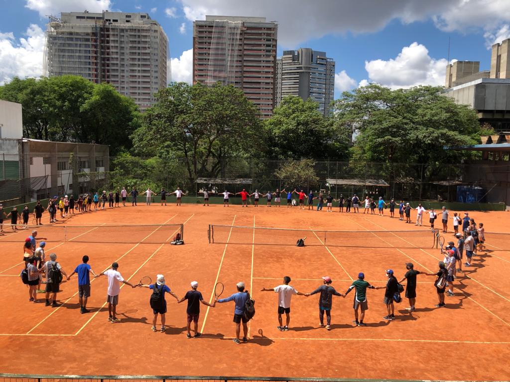 Imagem mostra tenistas amadores dando as mãos em volta de quadra de tênis do Complexo Mané Garrincha
