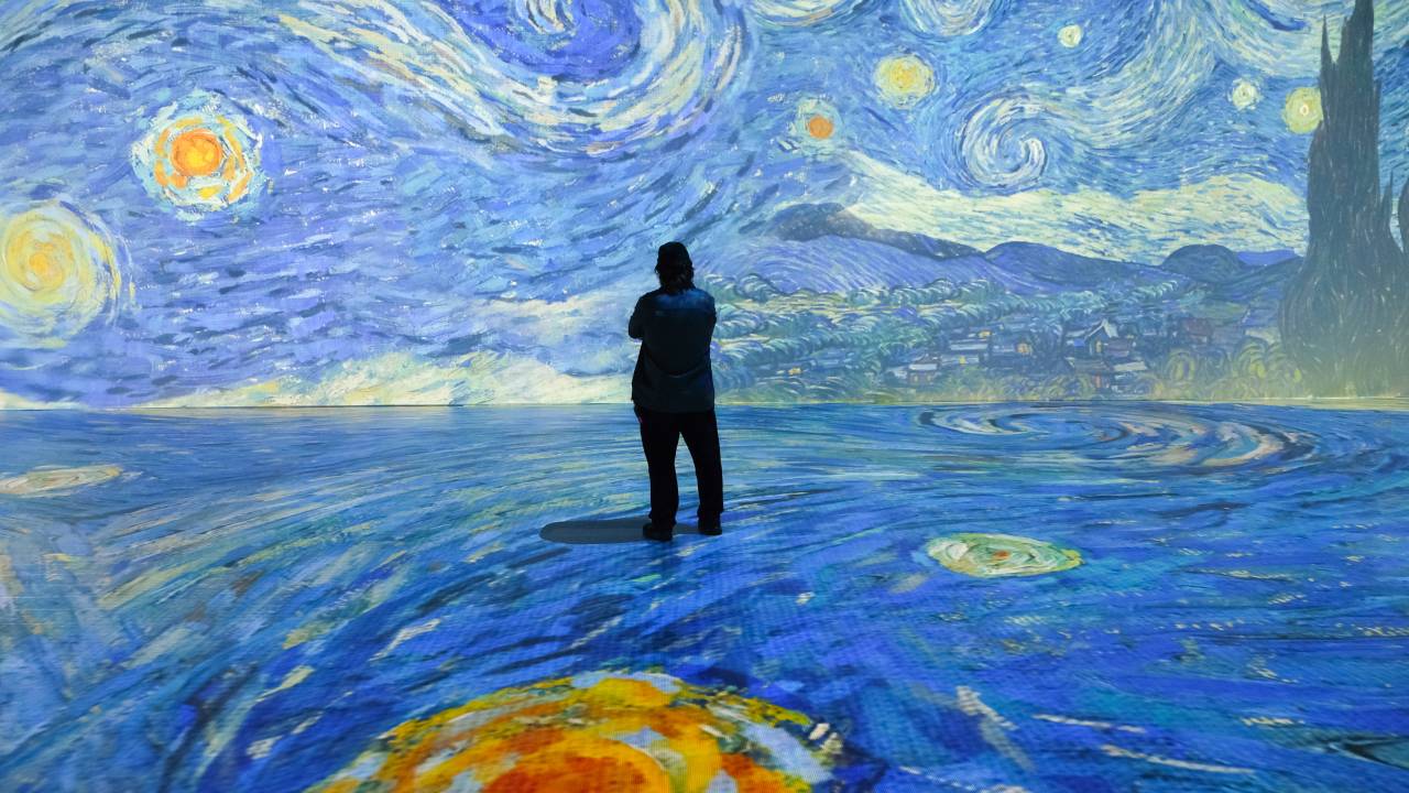 Homem em frente à projeção de imagem da tela Noite Estrelada de Van Gogh