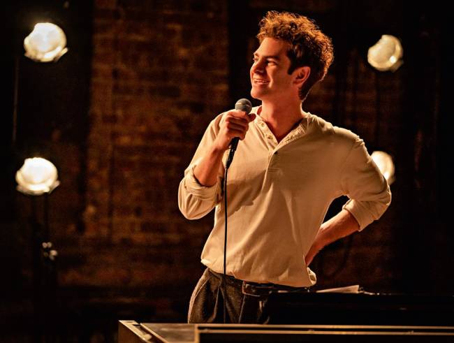 tick tick boom – credito Macall Polay Netflix.jpg Imagem mostra homem de camiseta branca falando com um microfone na mão. No fundo, luzes de palco.
