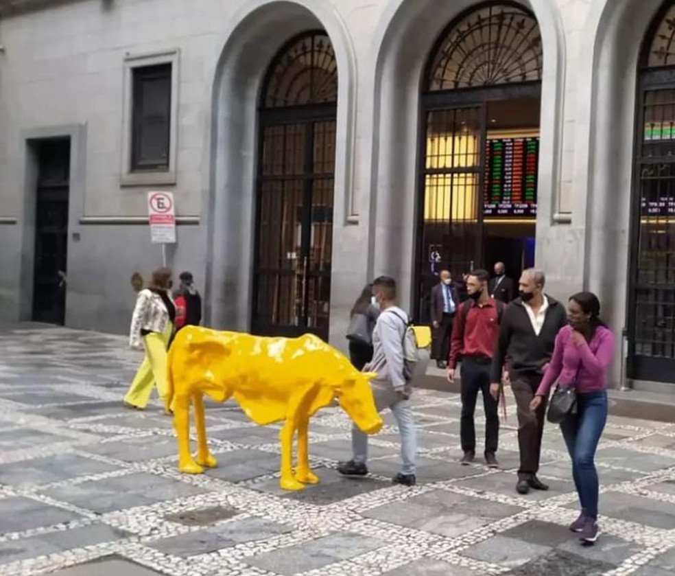 A imagem mostra uma escultura de vaca em meio à calçada no centro de São Paulo