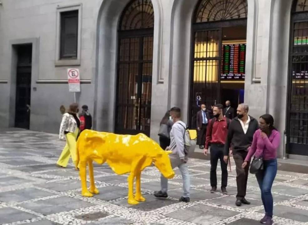 A imagem mostra uma escultura de vaca em meio à calçada no centro de São Paulo