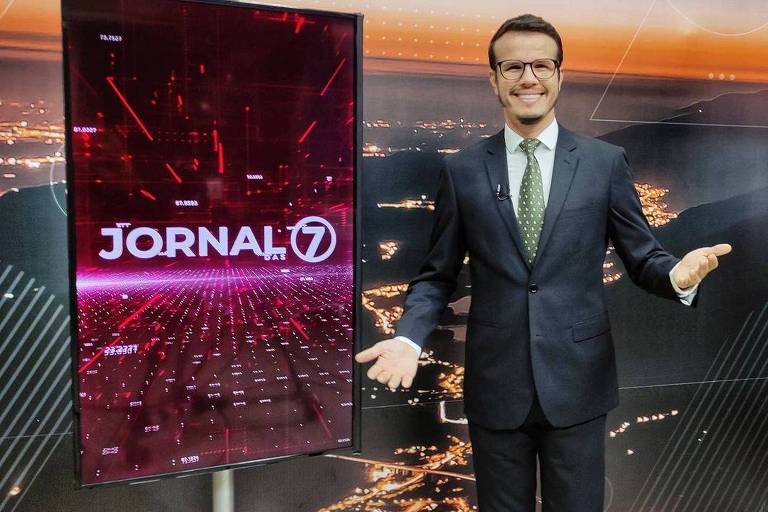 Imagem mostra homem de terno e gravata verde ao lado de tela com o escrito "Jornal das 7".
