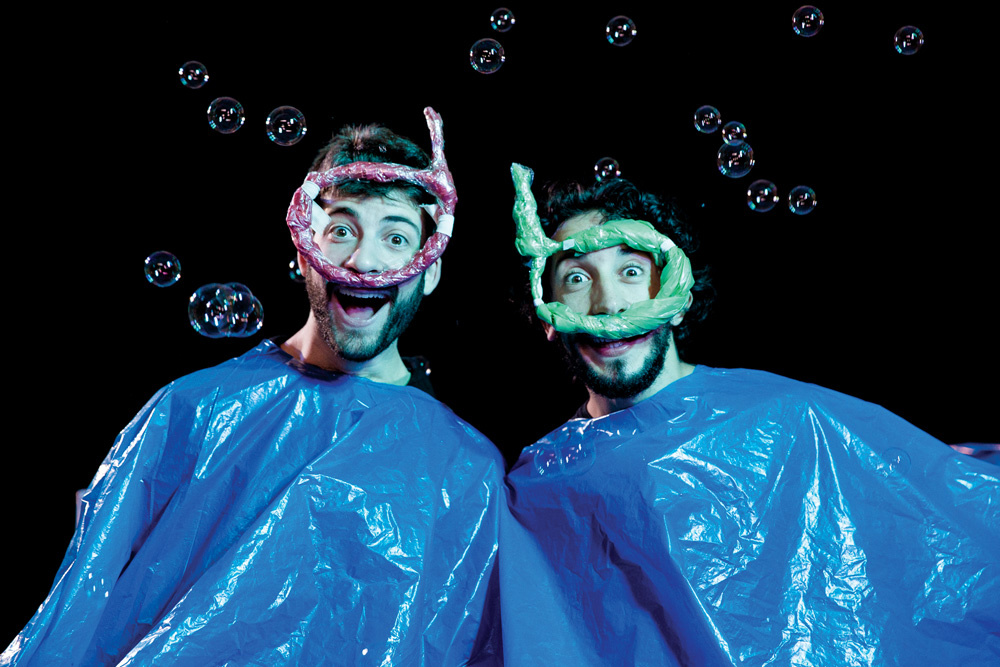 Foto mostra dois atores usando como fantasia sacos plásticos azuis.