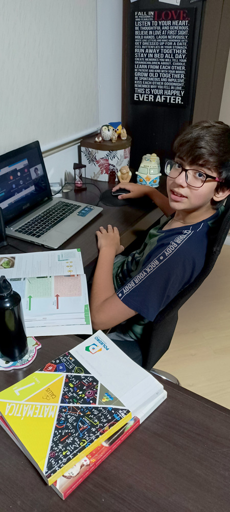 Matheus aparece estudando em sua escrivaninha. Ele usa óculos e olha para a câmera.