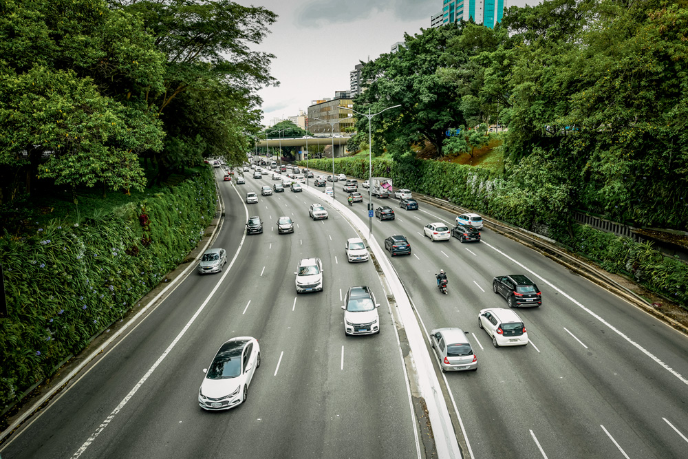 Imagem mostra avenida com paredões verdes com jardins suspensos de ambos os lados.