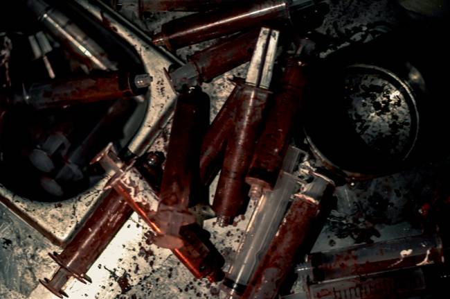 Imagem mostra conjunto de seringas ensanguentadas jogadas no chão.