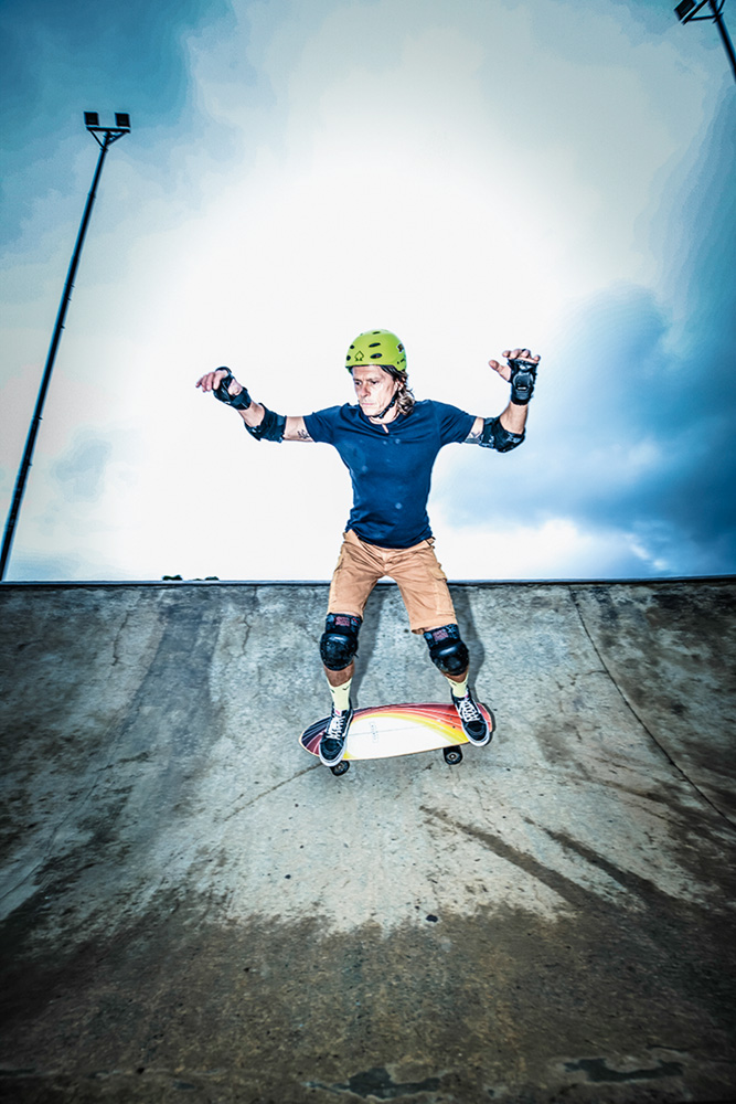 Imagem mostra homem com os braços levantados, sobre skate, em rampa.