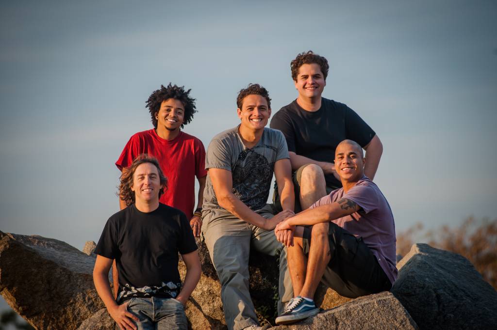 Imagem mostra 5 homens sobre pedras, sorrindo para a foto.