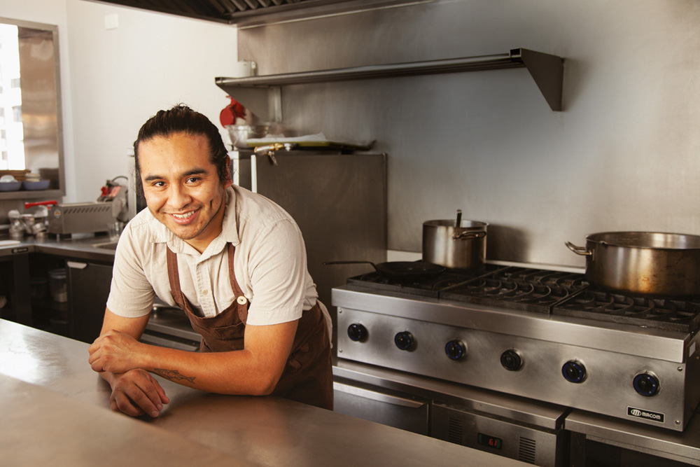 Chef posa com avental de cor marrom em uma cozinha