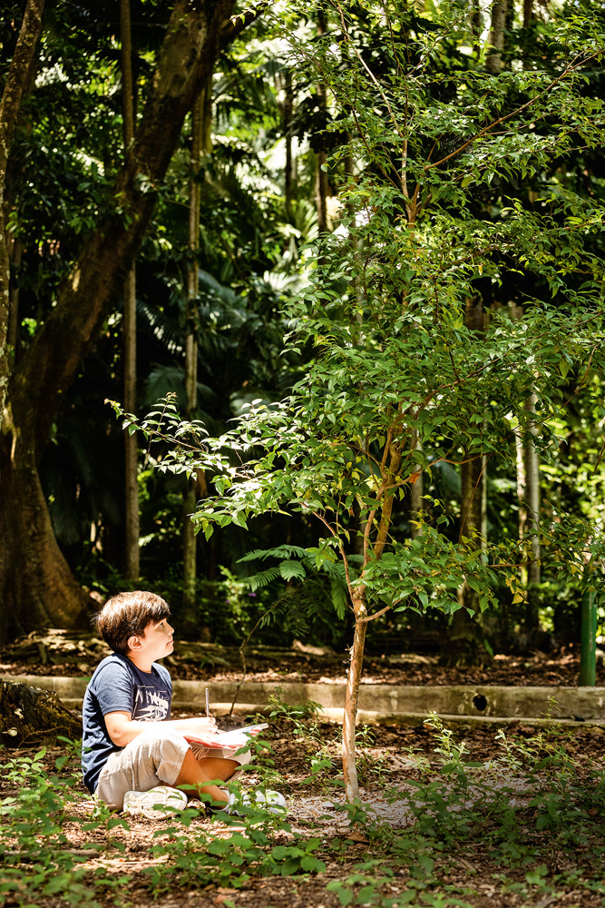 Pablo aparece sentado embaixo de uma árvore que plantou no Parque Estadual da Água Branca.