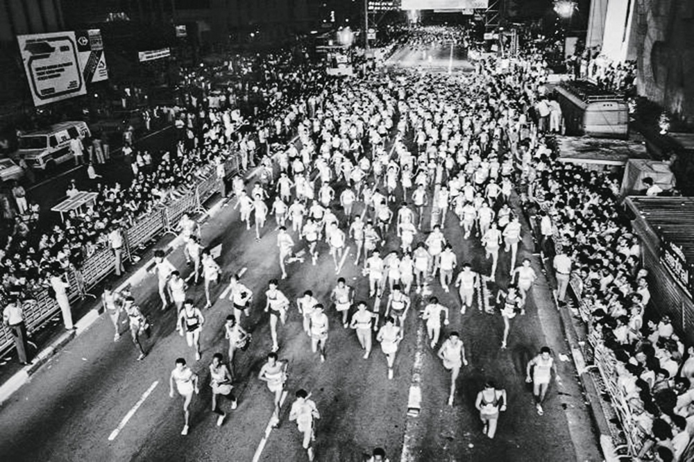 Imagem mostra multidão de pessoas correndo em avenida.