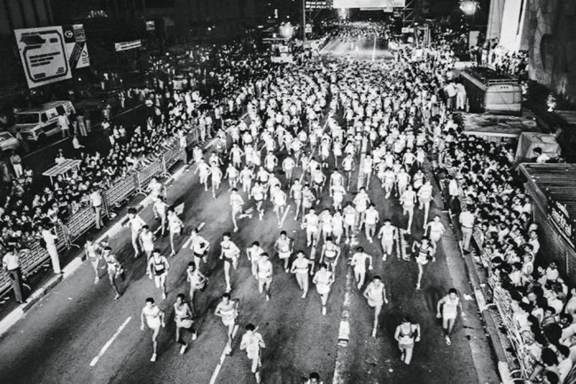 Imagem mostra multidão de pessoas correndo em avenida.