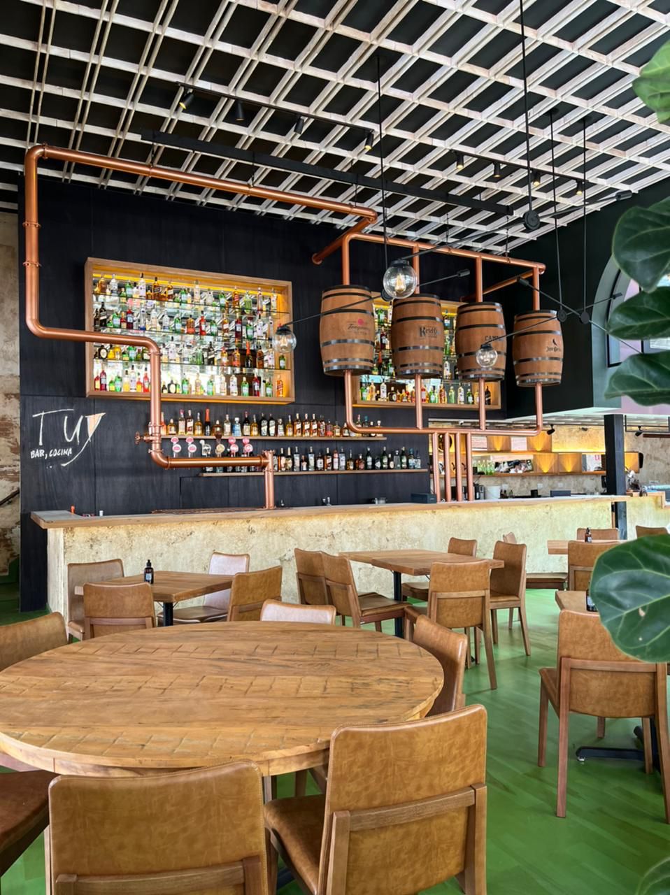 Ambiente de bar com garrafas expostas e barris de madeira como parte da decoração