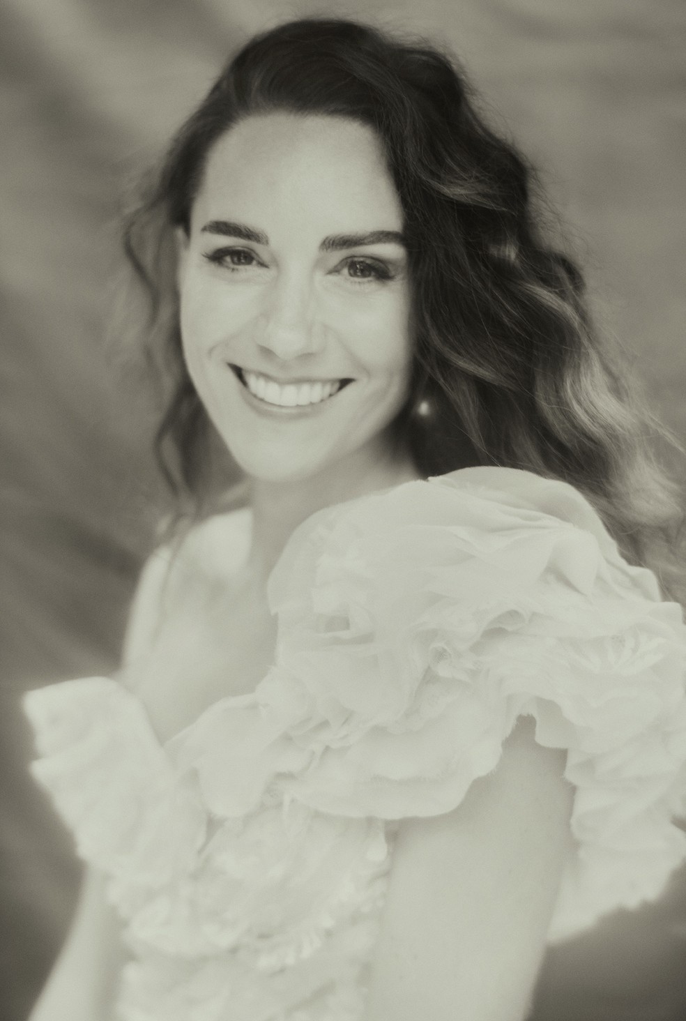 Imagem em preto e branco mostra Kate Middleton de vestido branco, sorrindo