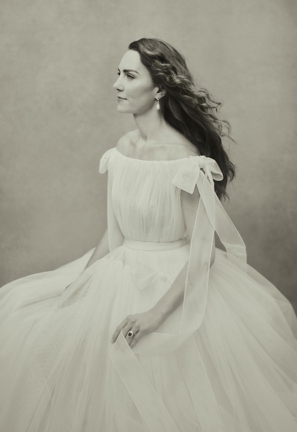 Imagem em preto e branco mostra Kate Middleton de vestido branco, olhando para a frente