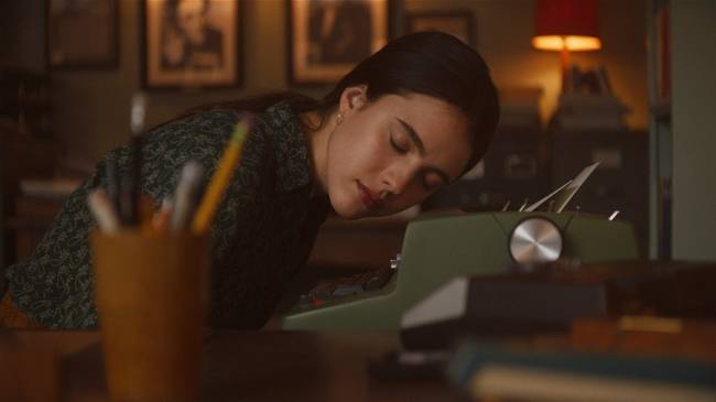 Na imagem, jovem dorme apoiada em uma máquina de escrever