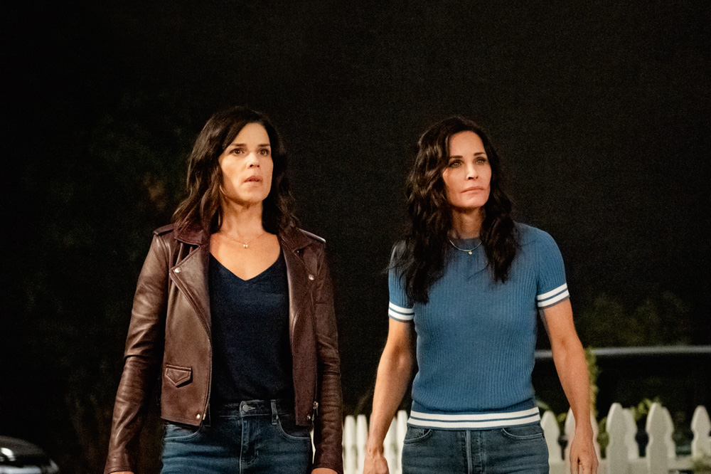 Imagem mostra duas mulheres, uma de jaqueta marrom e outra de camiseta azul. Elas olham para o mesmo ponto, à direita da câmera, assustadas.