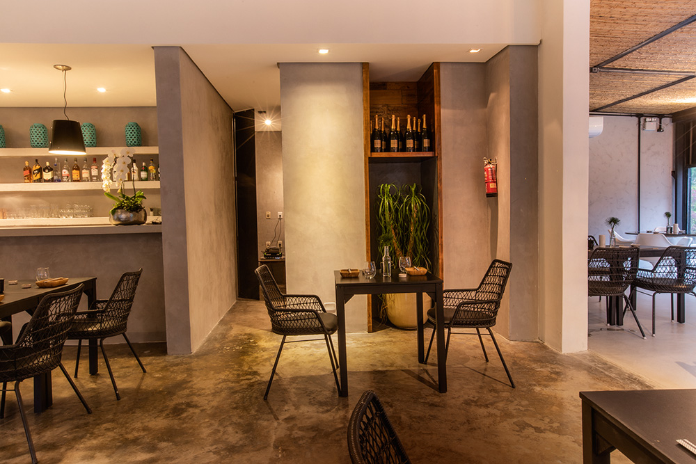Ambiente de restaurante com paredes cinzas e cadeiras e mesas de cor marrom