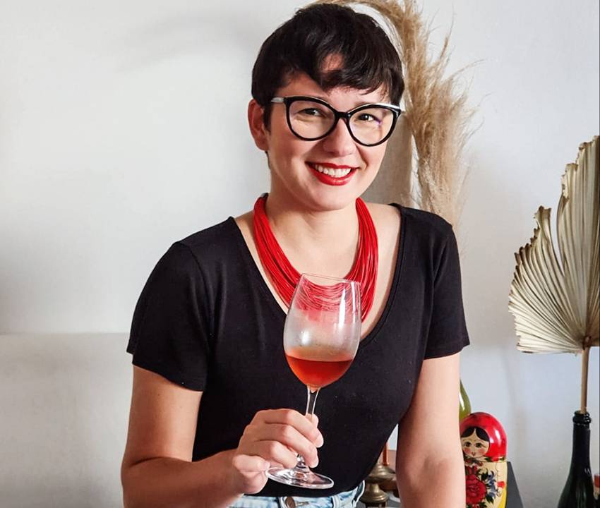 Jessica Marin­zeck posa segurando uma taça de vinho rosé em sua mão direita