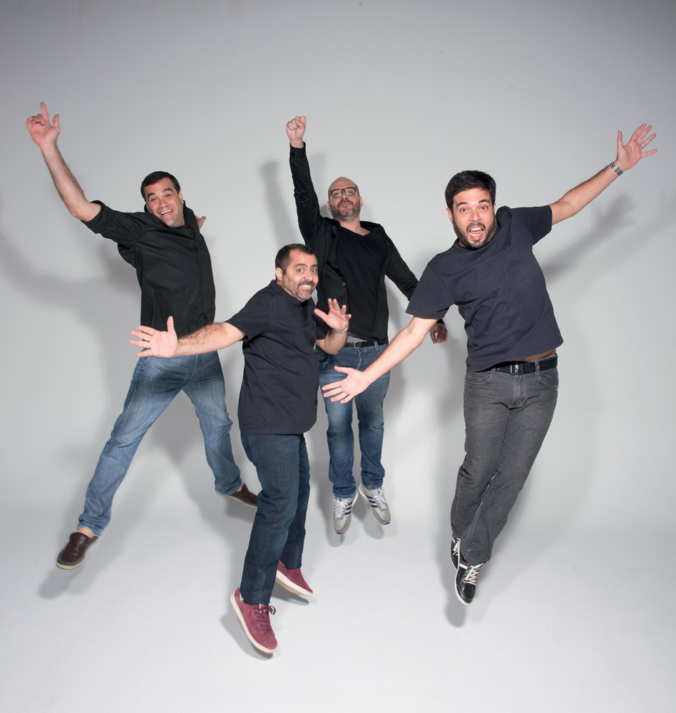 três homens vestem camiseta preta e calça jeans e abrem os braços em foto de divulgação do grupo musical