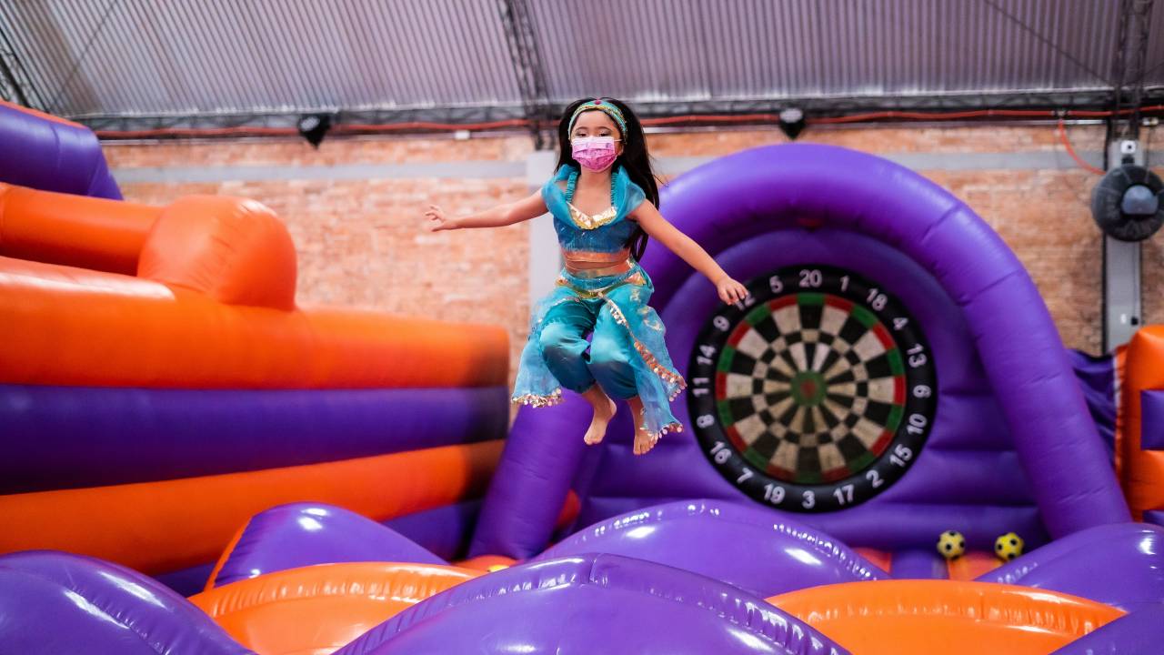 Menina pula em brinquedo inflável vestida com uma fantasia