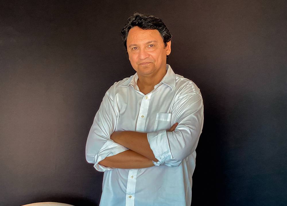 Marcelo Copello posa de braços cruzados enquanto usa uma camisa branca