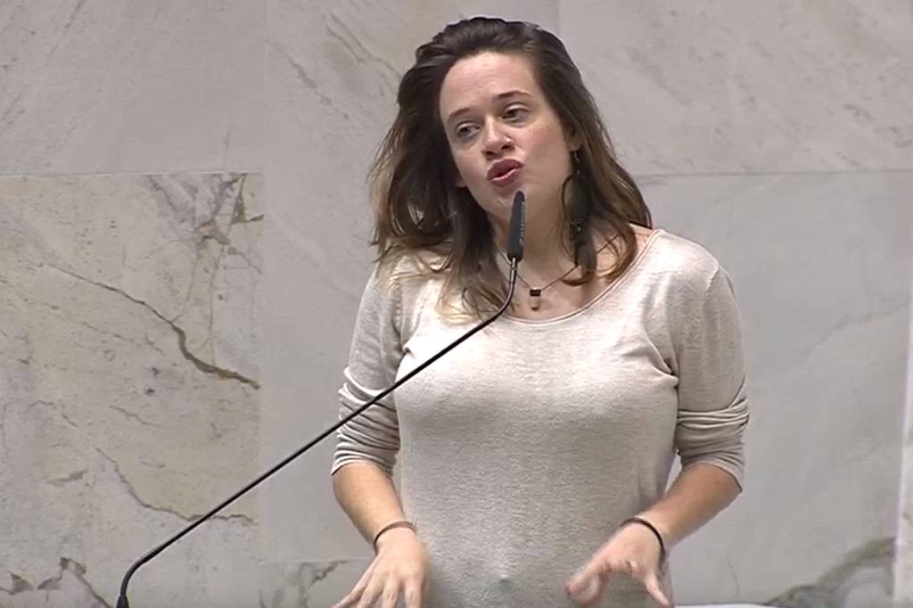 Imagem mostra mulher de roupa branca discursando em plenário.