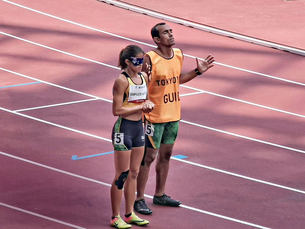 Imagem mostra uma mulher e um homem em uma pista de corrida, parados um ao lado do outro.