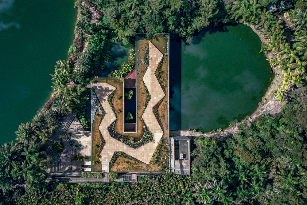 Imagem aérea mostra lago ao lado de construção com terraço em formato retangular.