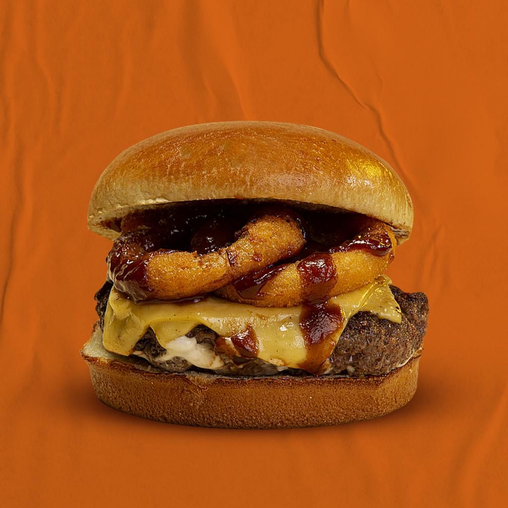 flip burger Hambúrguer com cebola empanada dentro em fundo laranja.