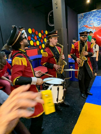Banda com roupas coloridas de Carnaval tocando no Museu da Imaginação