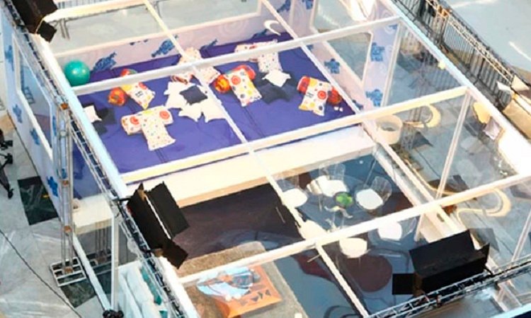Imagem do alto mostra ambiente envidraçado com travesseiros e almofadas espalhados pelo chão