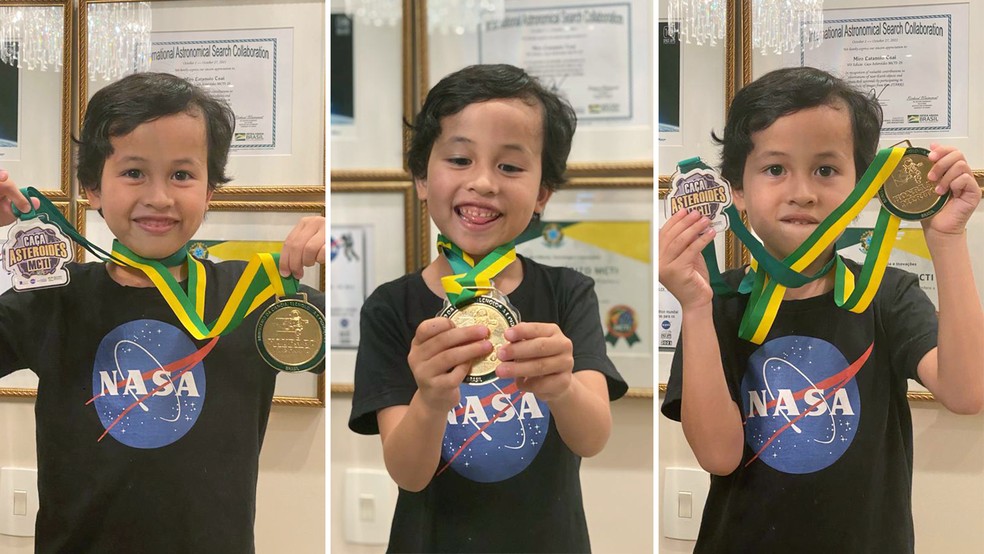 Imagem de Miro vestindo uma camiseta com o logo da NASA e segurando medalhas