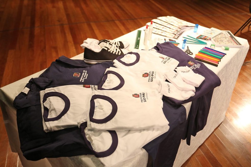 blusas e camisetas do uniforme das escolas públicas de SP dobras em cima de uma mesa