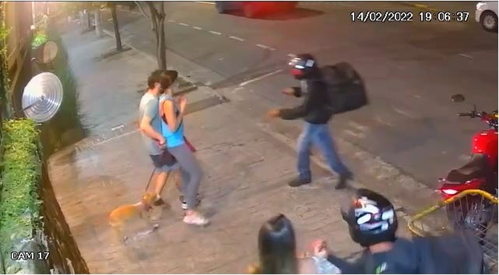 A imagem mostra bandidos disfarçados de entregadores roubando pedestres na calçada