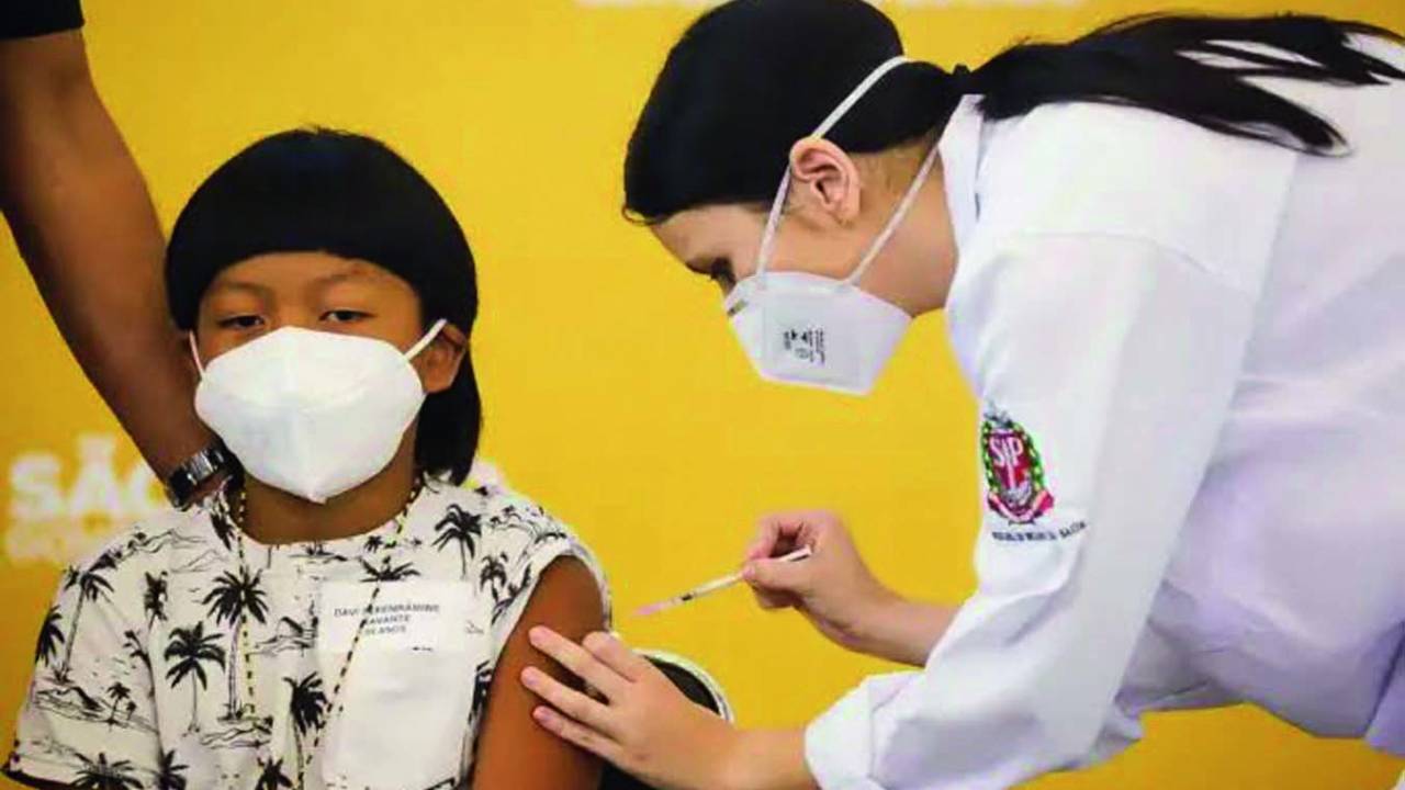 Imagem mostra menino indígena sendo vacinado
