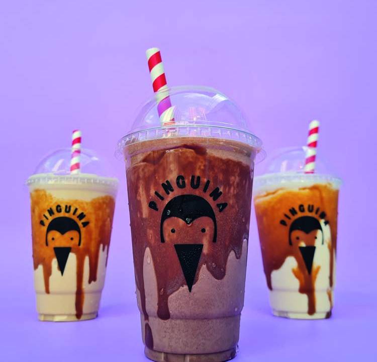 Três copos de plásticocom o logo da Pinguina com milk-shake