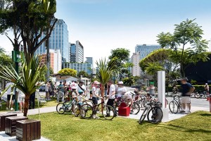 Imagem mostra praça com gramado e diversas bicicletas.