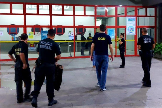 homens com camiseta da polícia federal entram em prédio