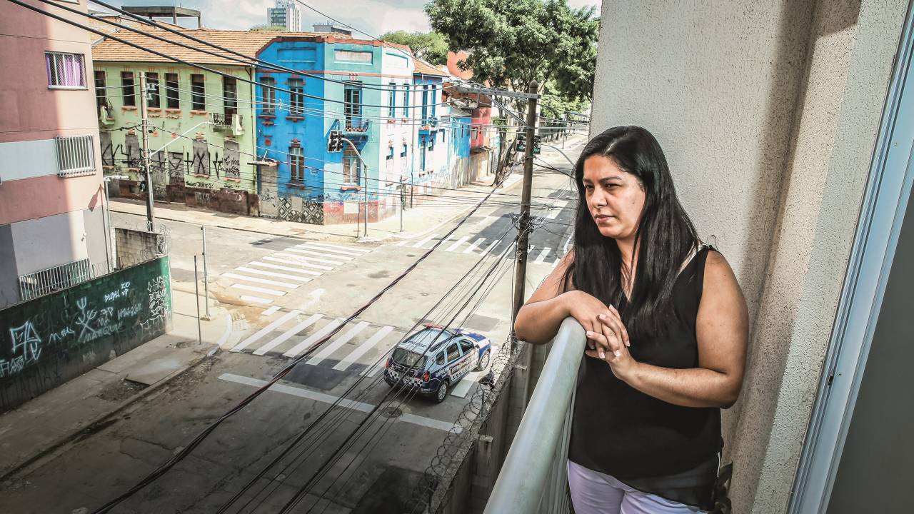 Imagem mostra mulher na sacada de um prédio, com uma rua vazia e com apenas um carro passando