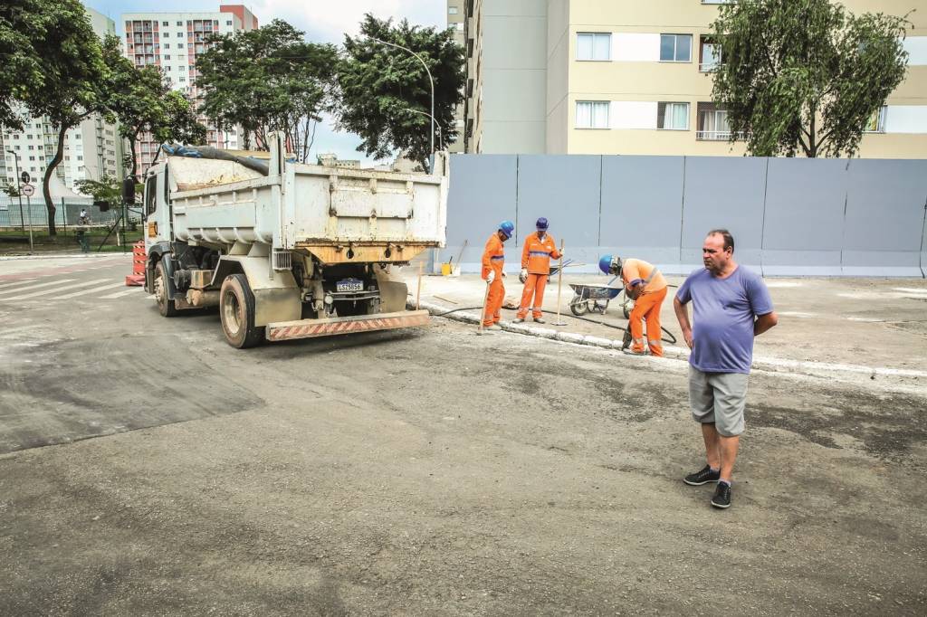 Imagem mostra homem posando à frente de três homens da prefeitura, um deles com britadeira