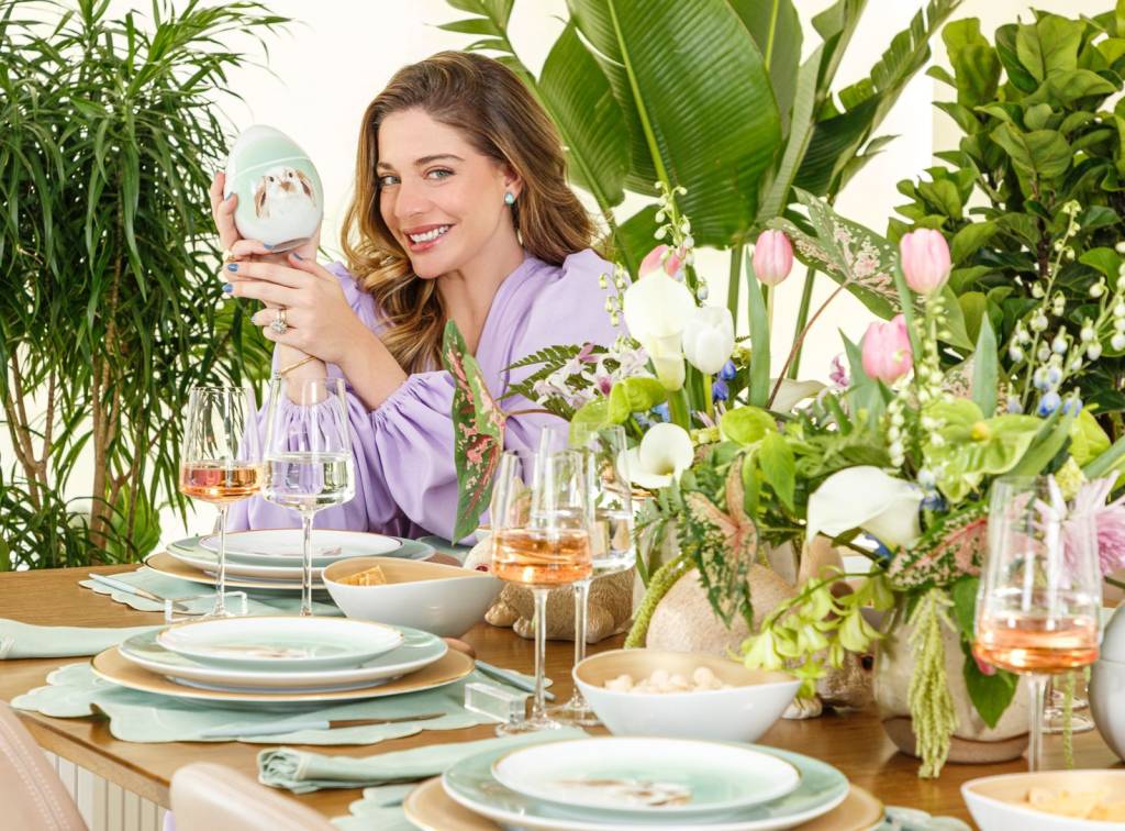 A atriz e empresária Luma costa aparece segurando item na mão em frente a mesa posta com pratos de temática da Páscoa.