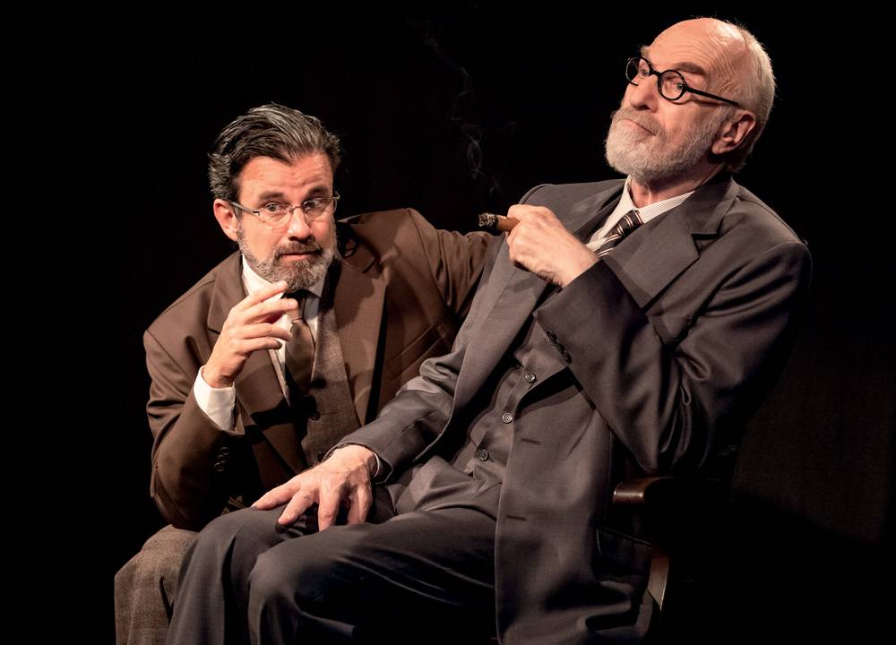 Dois atores contracenam no palco. Sigmund Freud é um senhor branco, calvo, de óculos, barba e cabelos grisalhos. Ele fuma um charuto e está sentado ouvindo C.S. Lewis, um homem branco, grisalho e de óculos. Ambos usam terno (Freud usa um terno preto e C.S. Lewis, um terno marrom).