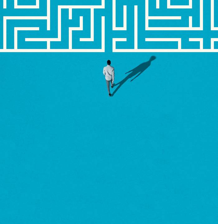 Uma ilustração em que um homem anda por labirintos gráficos brancos. O fundo é azul e a imagem é vista de cima, em perspectiva.