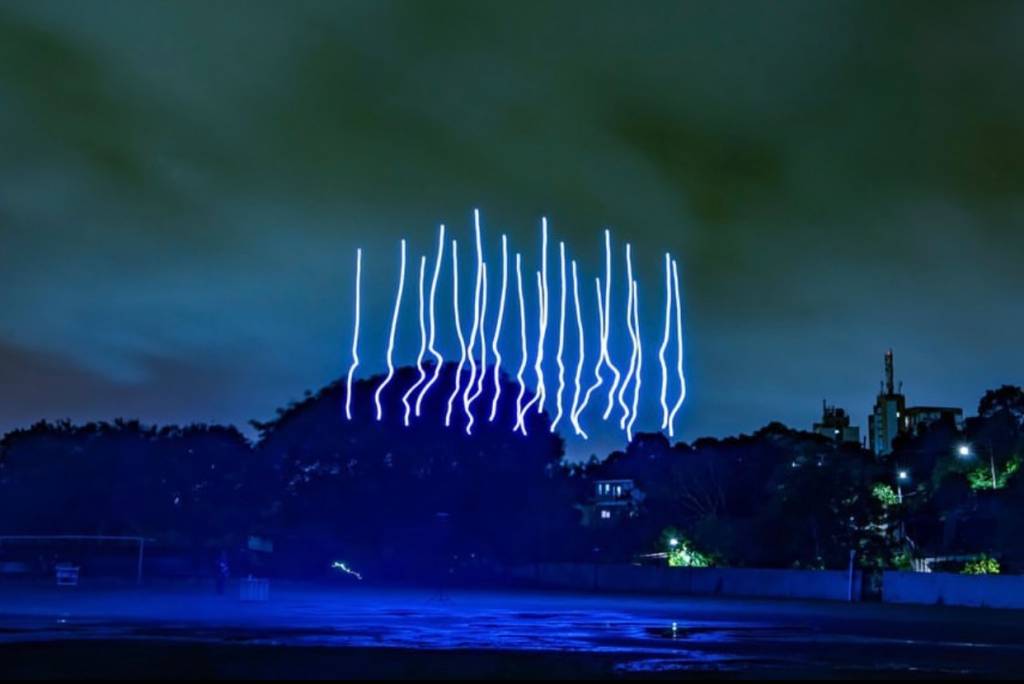 Imagem mostra projeção de luzes em formato de linhas rabiscadas azuis no céu.