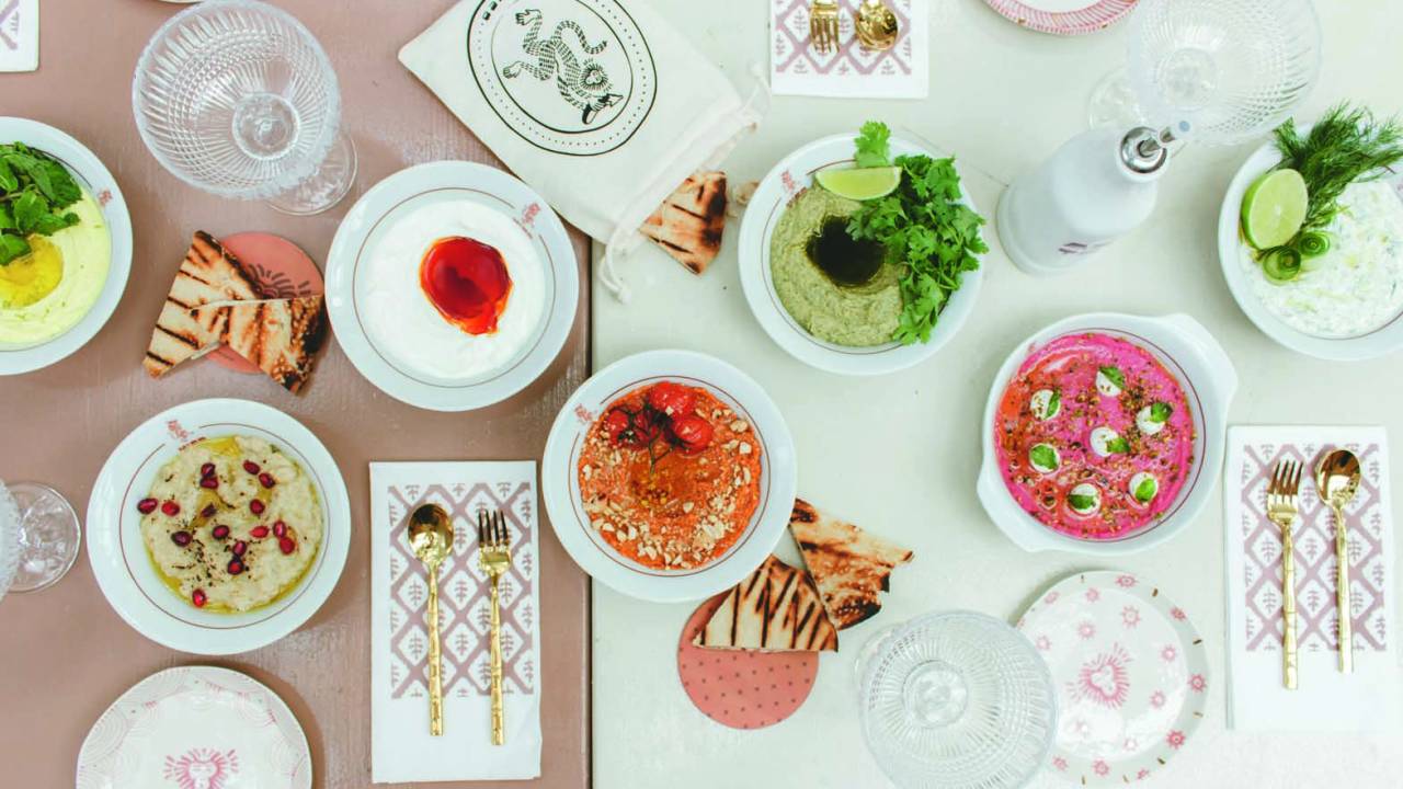 Visão de cima de uma mesa repleta de diferentes pratos de inspiração árabe