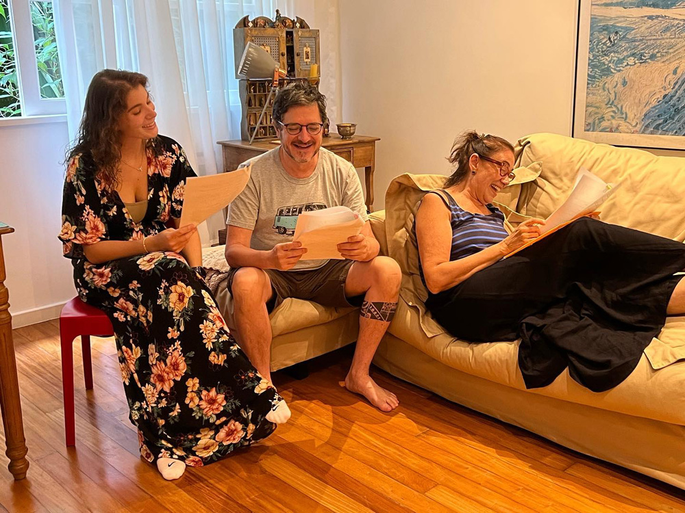 Lilia, sua filha e o diretor da peça estão na sala ensaiando o texto. Lilia está deitada no sofá e os outros dois sentados em cadeiras. Eles riem e seguram o script.