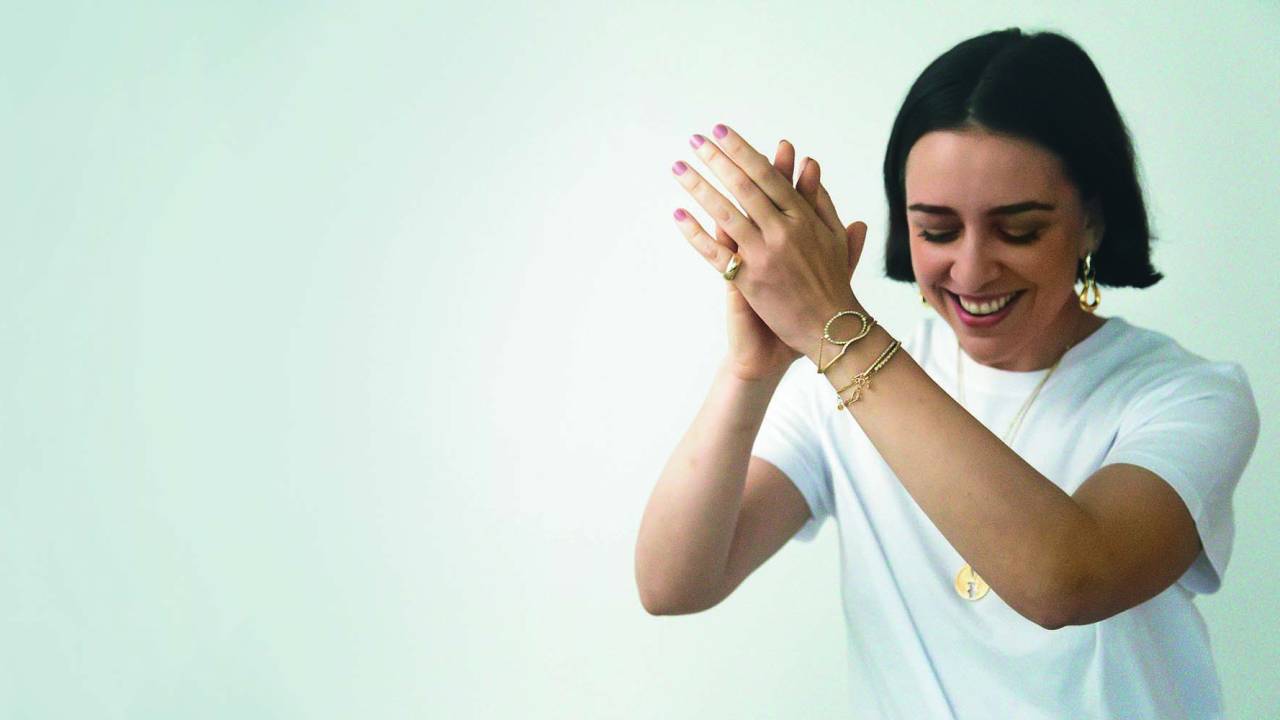 Imagem mostra mulher batendo palmas e sorrindo sobre fundo branco