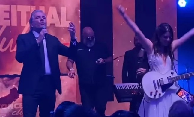 Imagem mostra Roberto Justus em um palco ao lado da filha, na guitarra