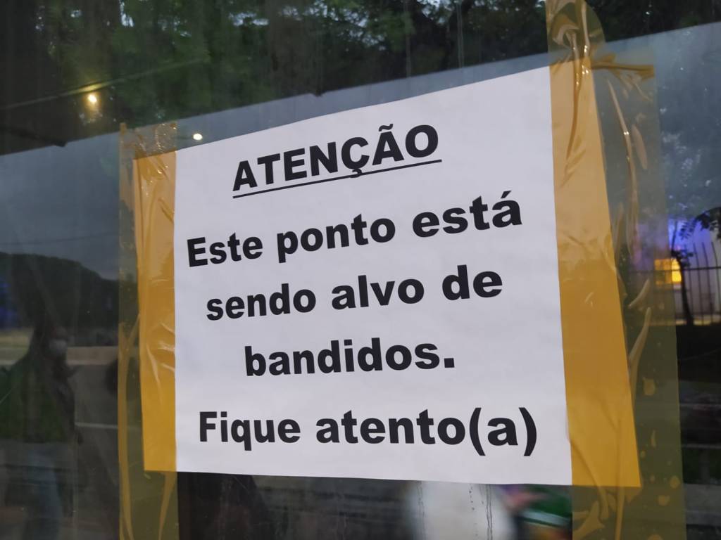 Cartaz em ponto de ônibus avisa que local é alvo de bandidos